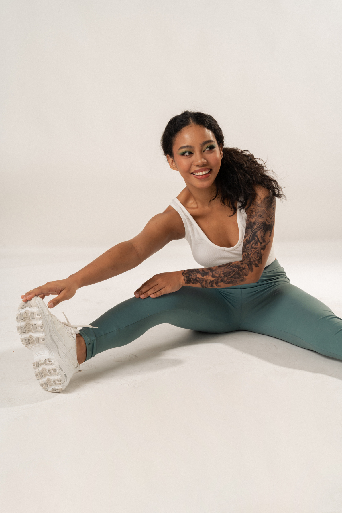 Woman in Activewear Stretching on White Background